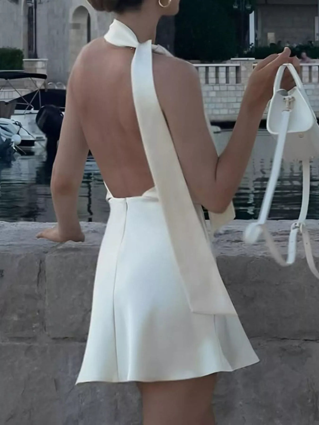 White halter mini dress with open back and V-shaped back neckline, flared skirt