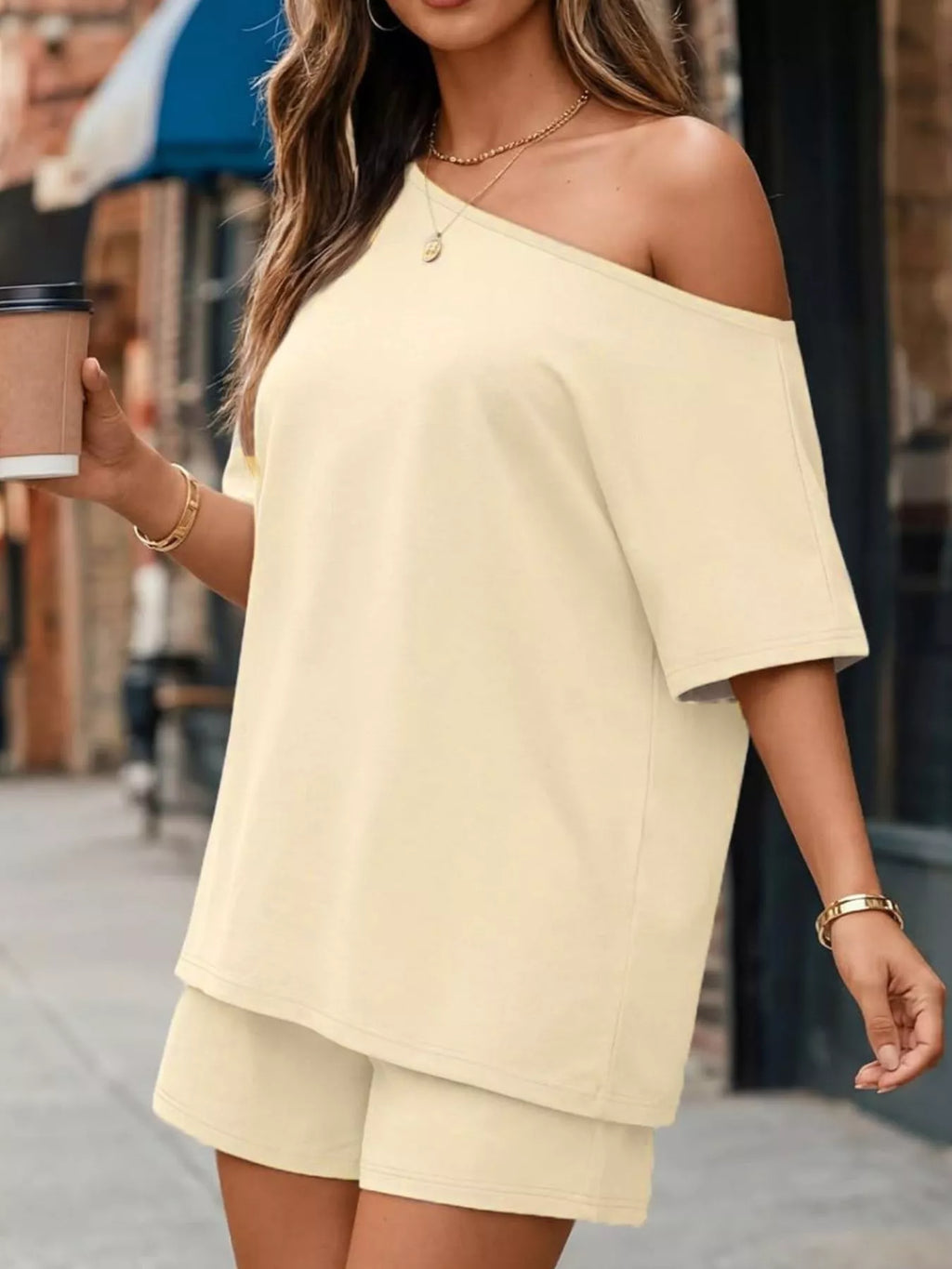 Cream one-shoulder short-sleeve top and matching shorts set with draped shoulder line.
