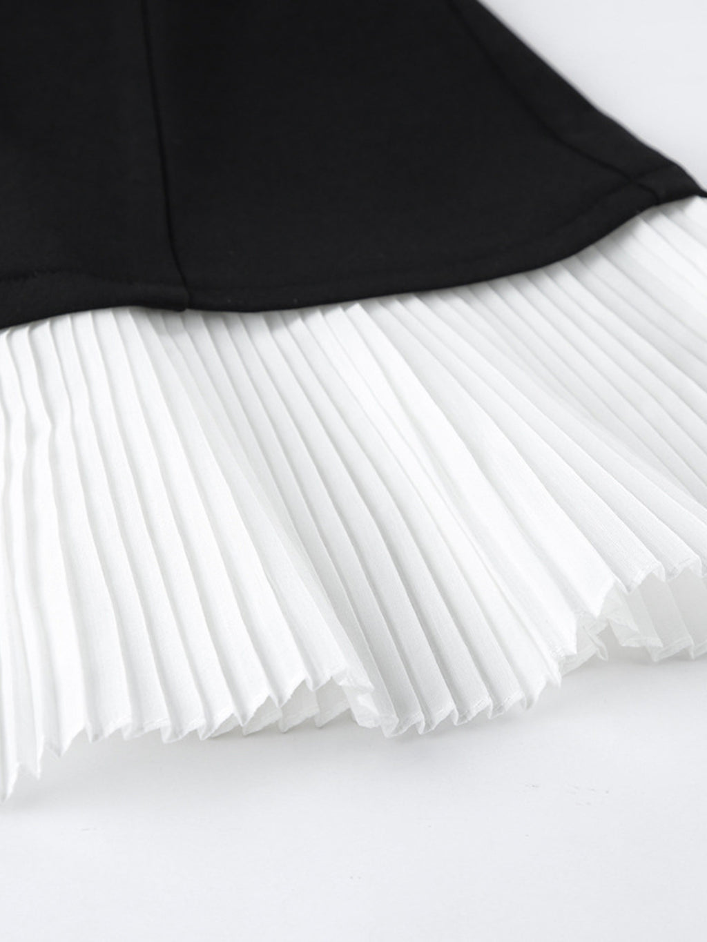 Pleated white skirt underlayer with black blazer hem above it