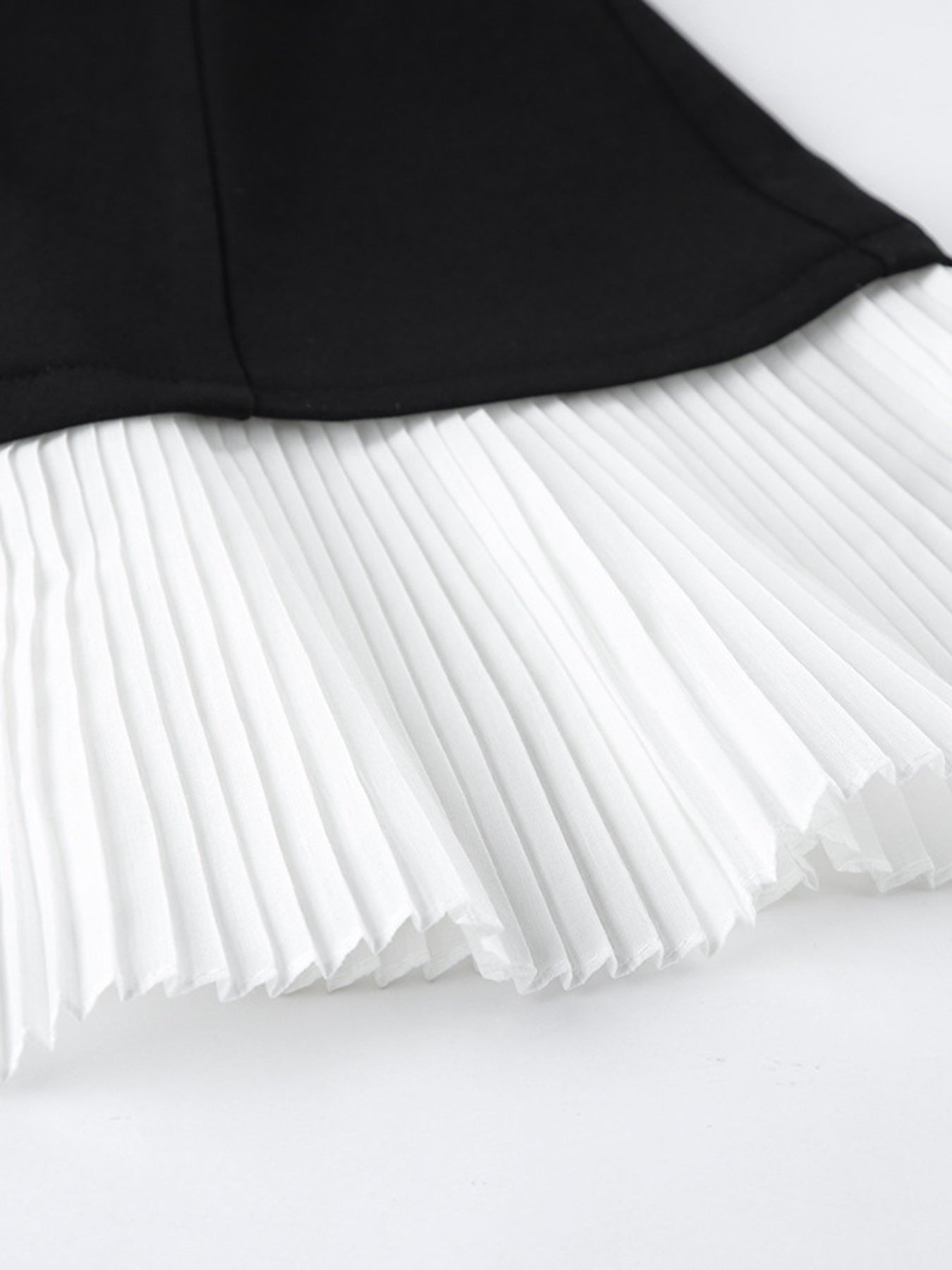 Pleated white skirt underlayer with black blazer hem above it