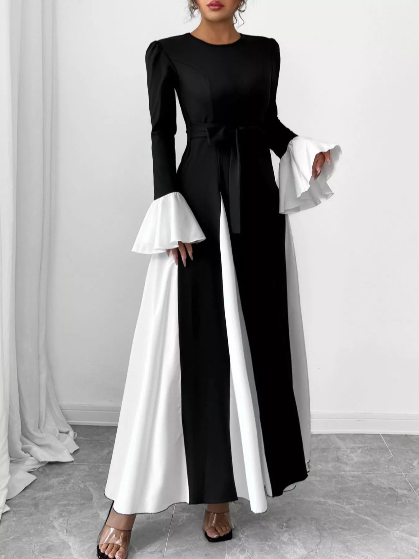Black maxi dress with long sleeves, round neck, and white ruffled cuffs