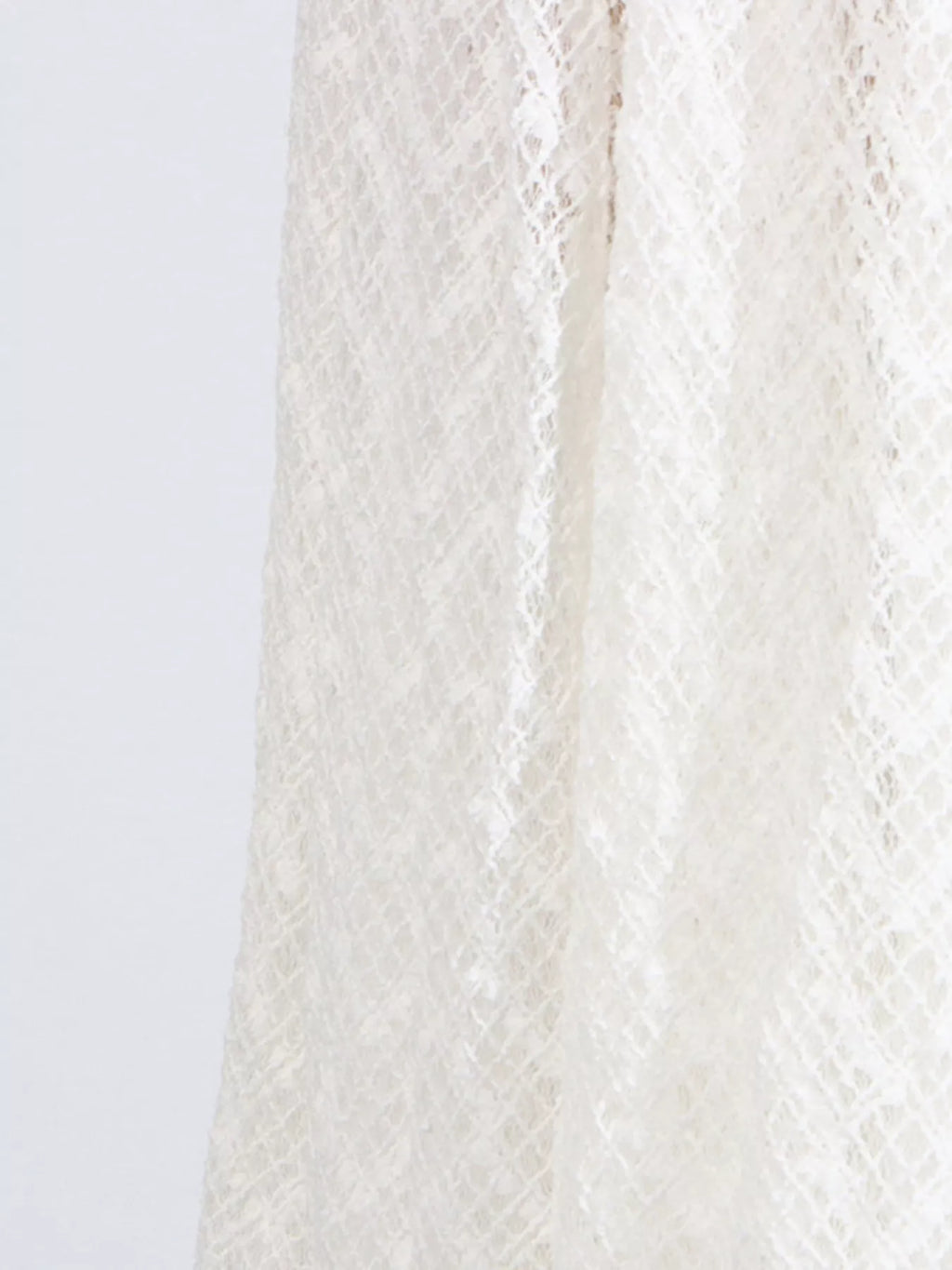 White lace long-sleeve maxi dress close-up of textured openwork fabric panel