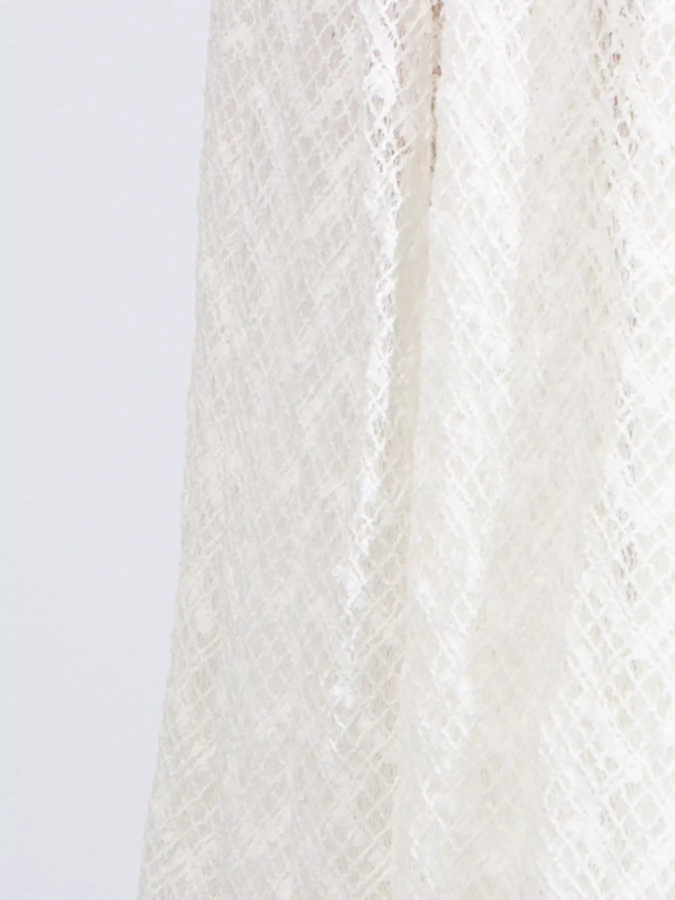 White lace long-sleeve maxi dress close-up of textured openwork fabric panel