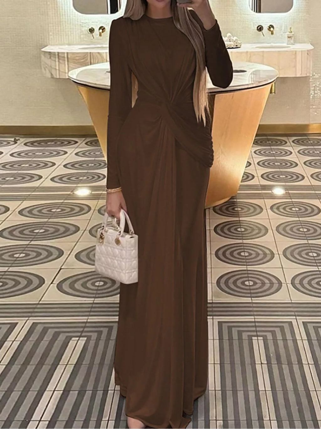 Brown twisted long-sleeve maxi dress with ruched knot at waist and straight flowing hem.