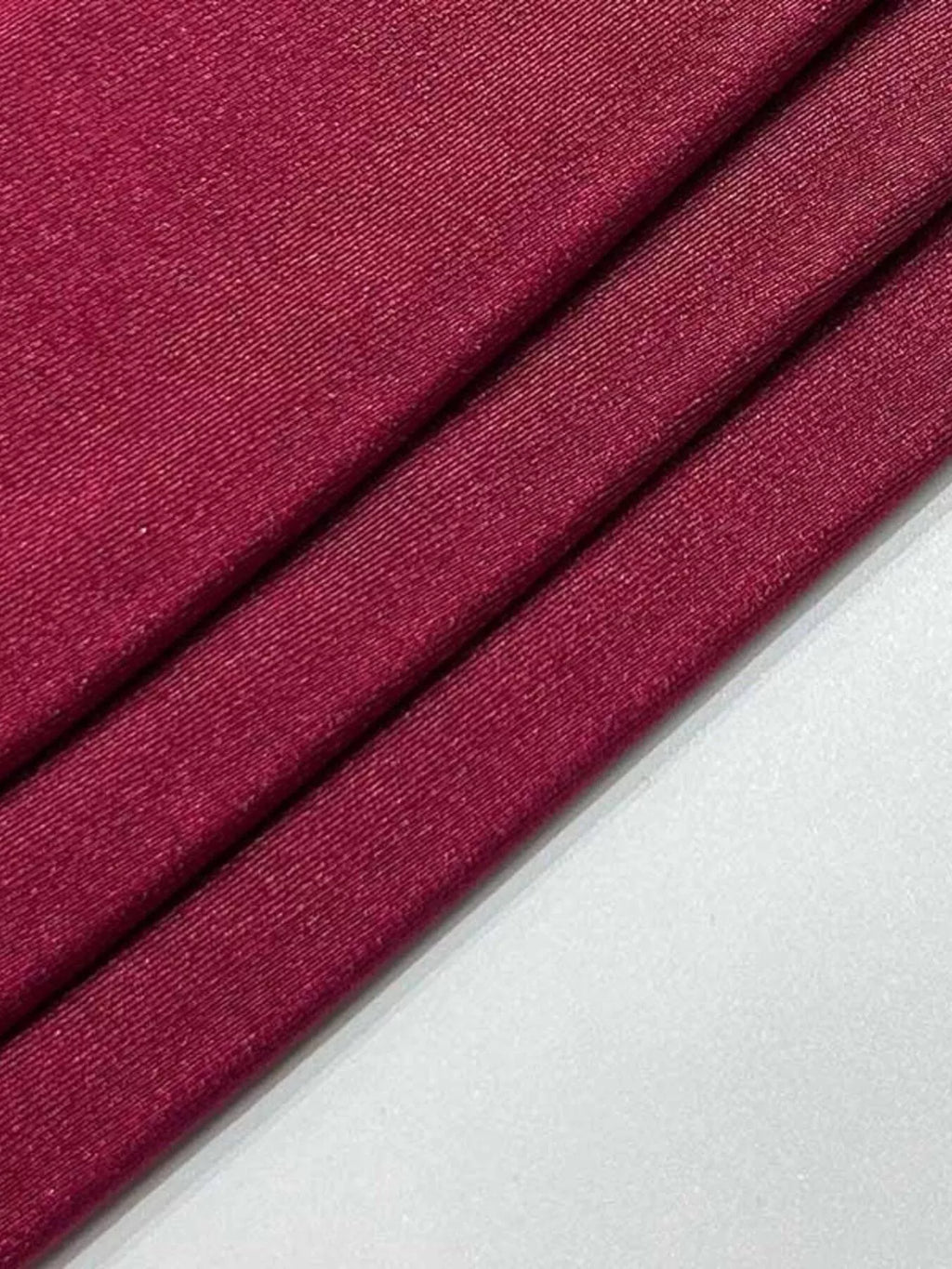 Burgundy fabric close-up with fine texture and visible stitched seam