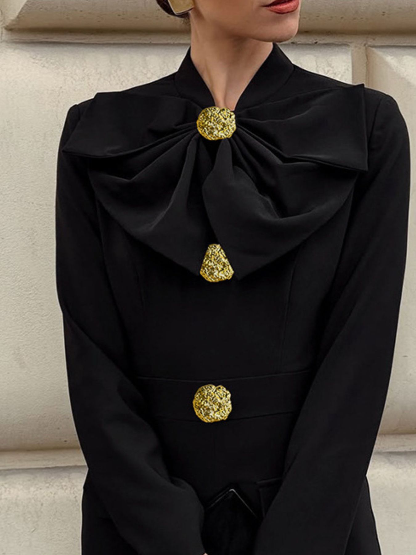 Close view of black midi dress ruffle collar with gold button detail at center.