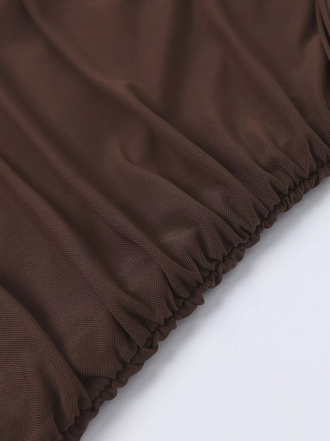 Brown ruched hem of an off-shoulder maxi dress with gathered edge