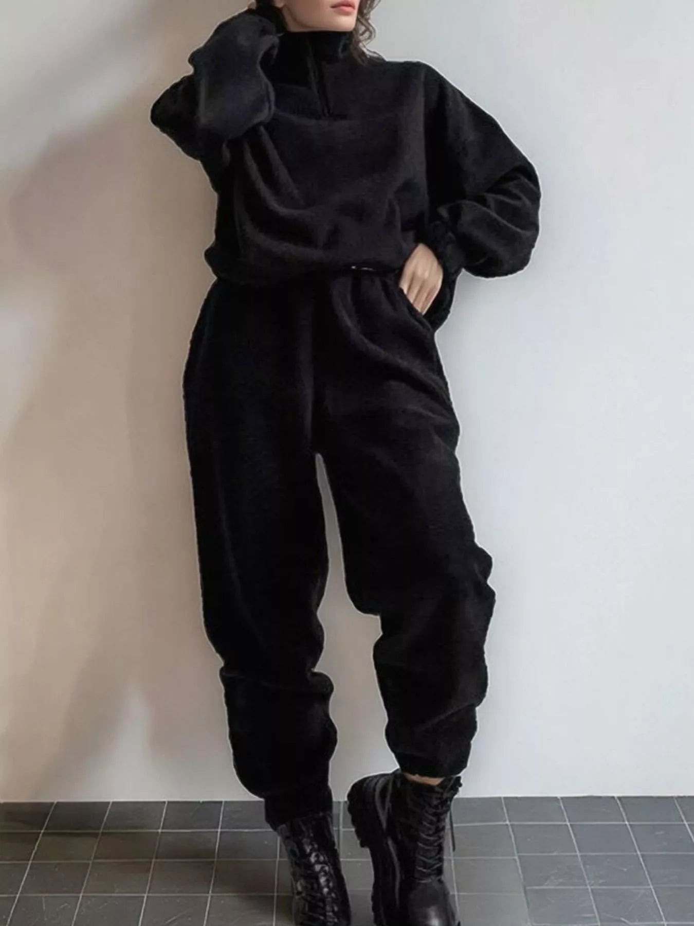 Black quarter-zip sweatshirt and jogger pants set on a model, full outfit view.