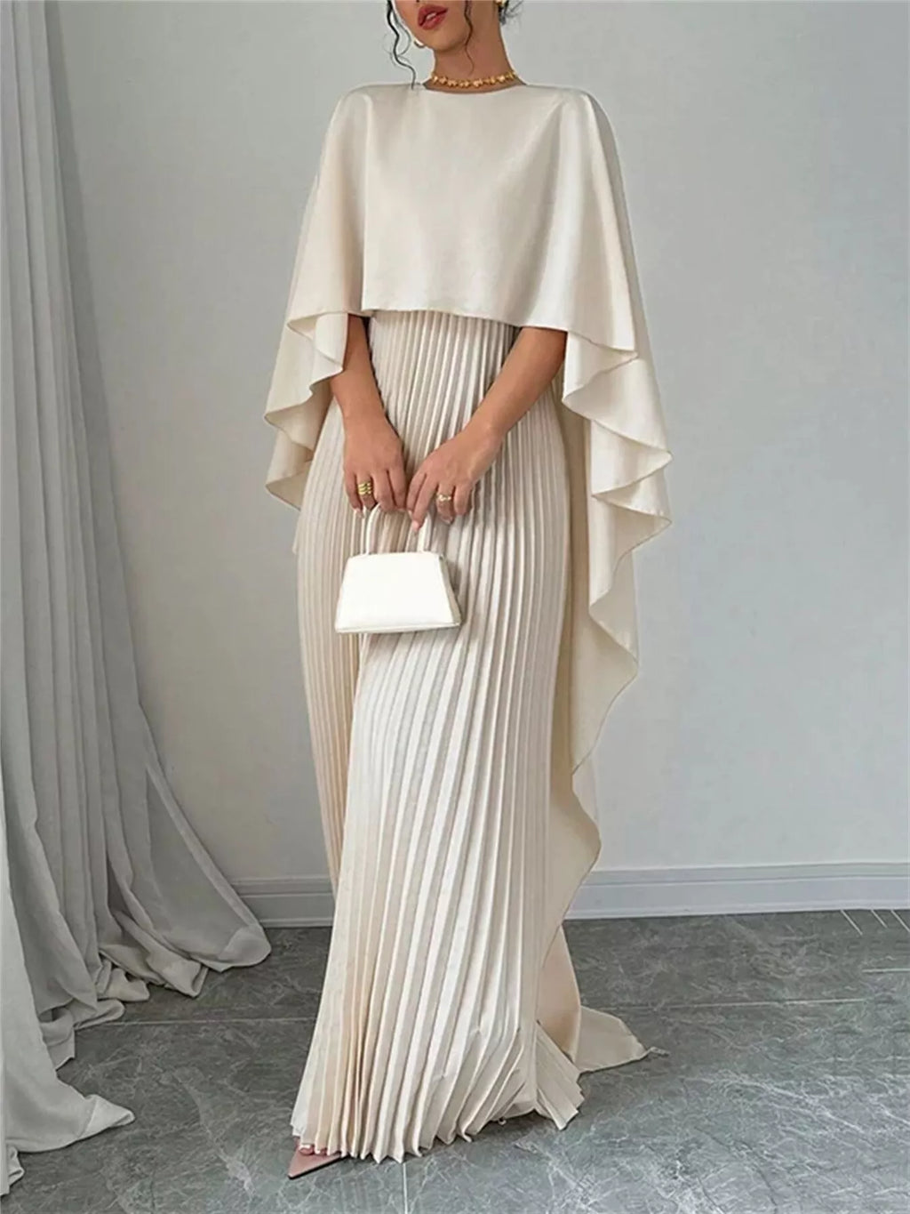 Cream cape pleated maxi dress with layered cape sleeves and long pleated column skirt