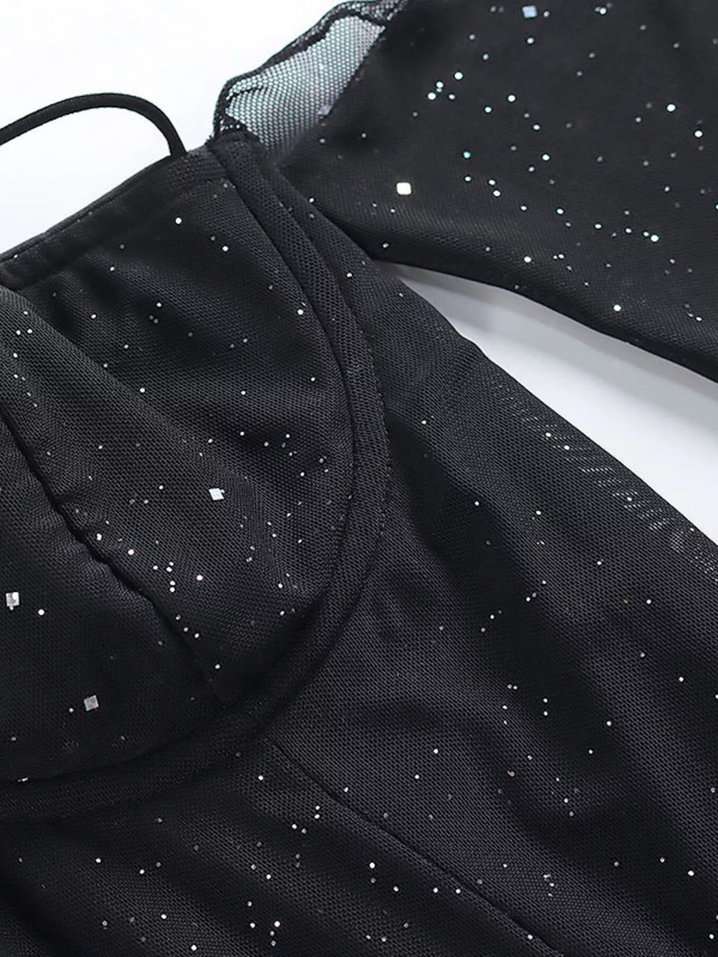 Close-up of black glitter mini dress fabric with dotted sparkle and sheer mesh sleeves