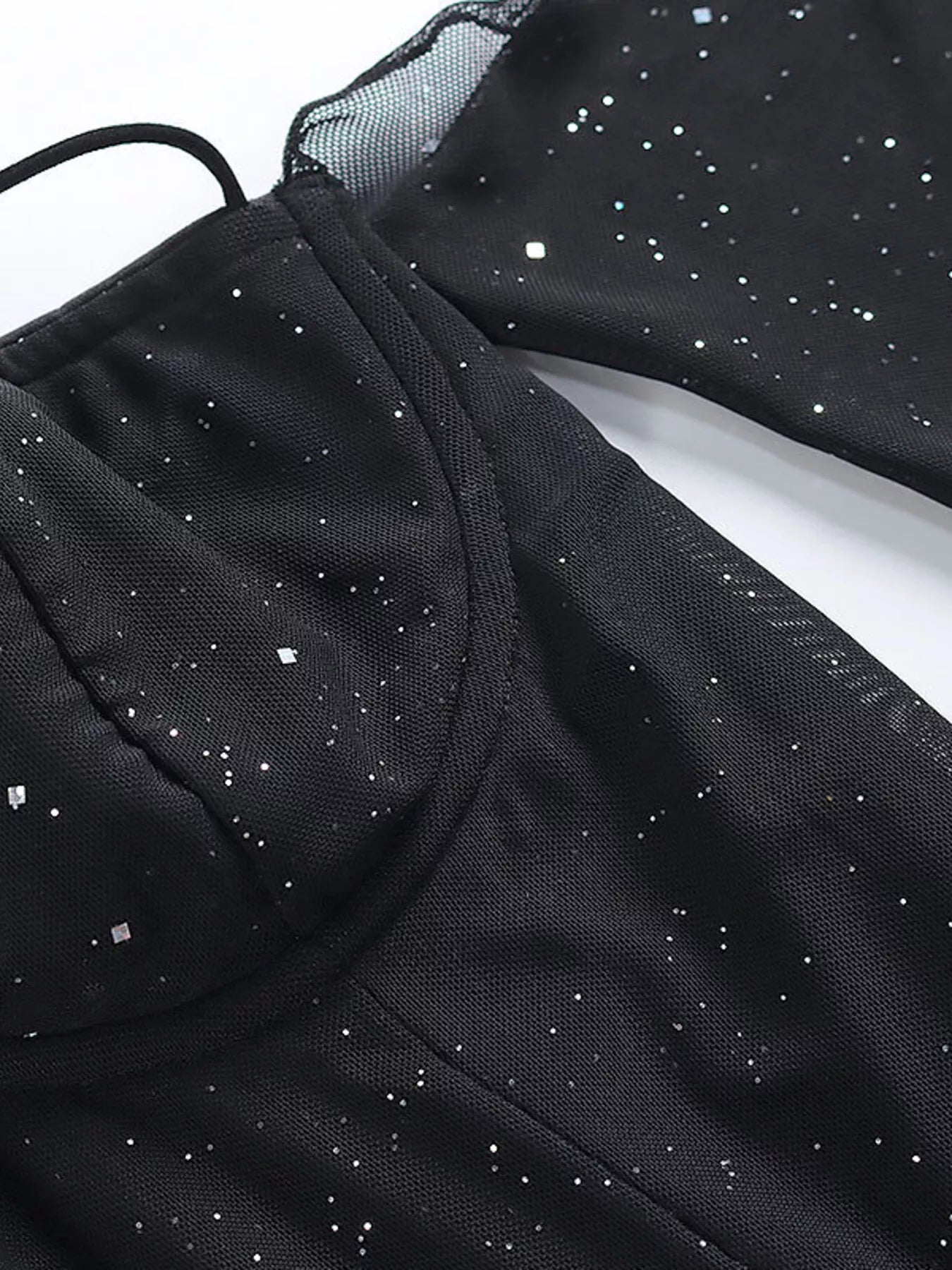 Close-up of black glitter mini dress fabric with dotted sparkle and sheer mesh sleeves