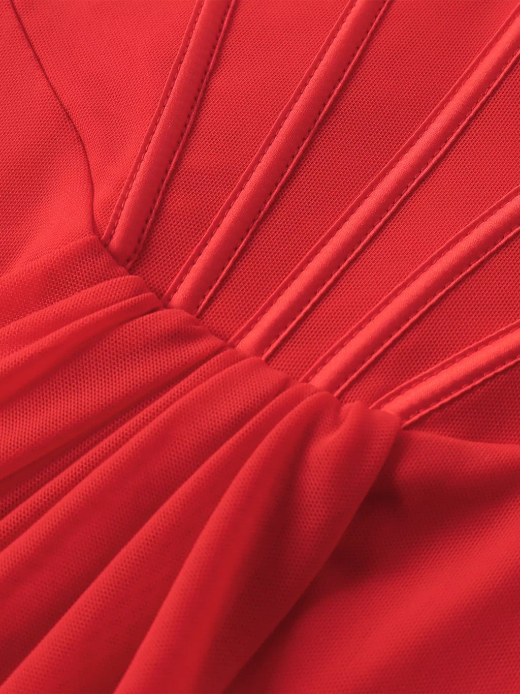 Close-up of red ruched mini dress fabric with vertical seam lines and gathered skirt