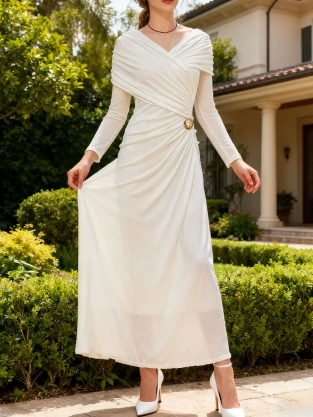 White ruched draped maxi dress with long sleeves, V-neck wrap, and gold ring waist detail.
