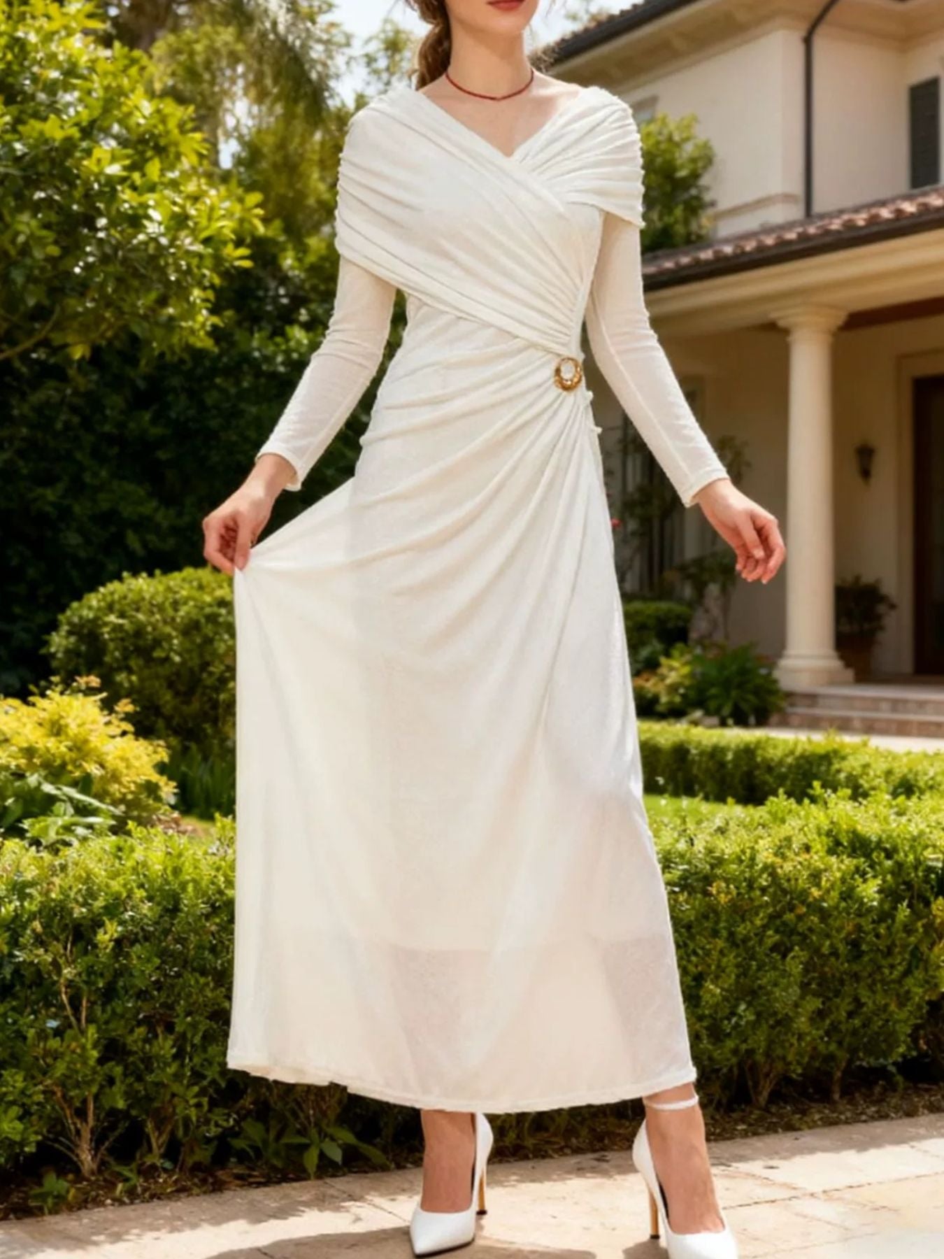 White ruched draped maxi dress with long sleeves, V-neck wrap, and gold ring waist detail.