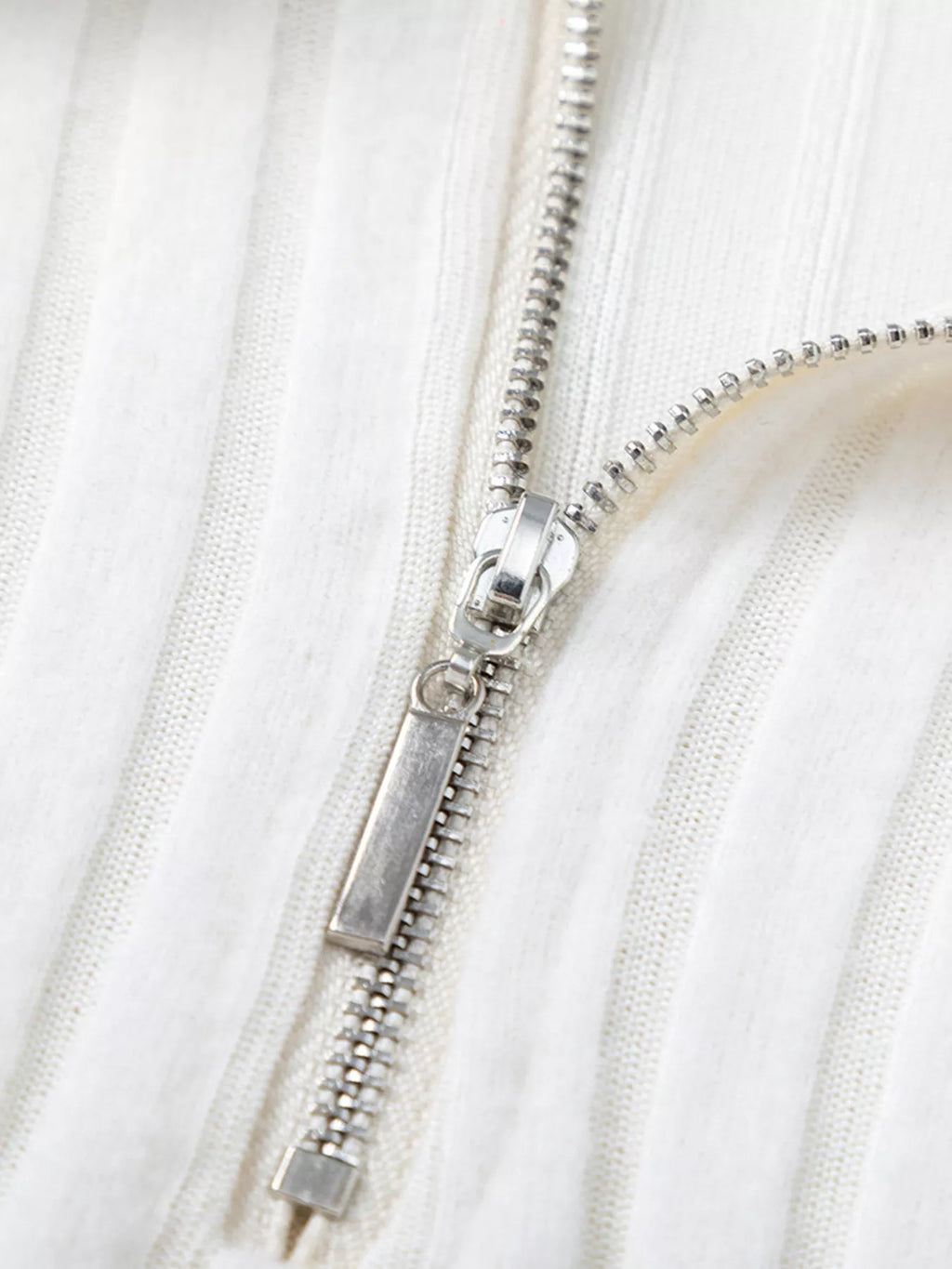White ribbed knit zipper detail with metal pull and track