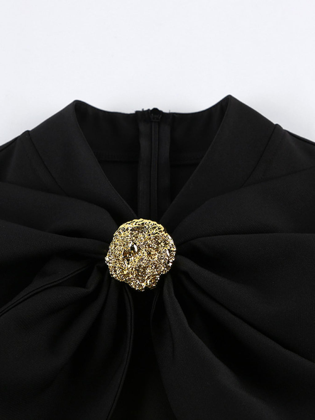 Detail of black ruffle collar with gold button centerpiece on long-sleeve dress.