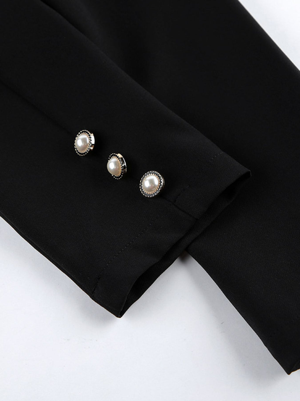 Black long-sleeve cuff with three pearl button accents and subtle seam stitching.