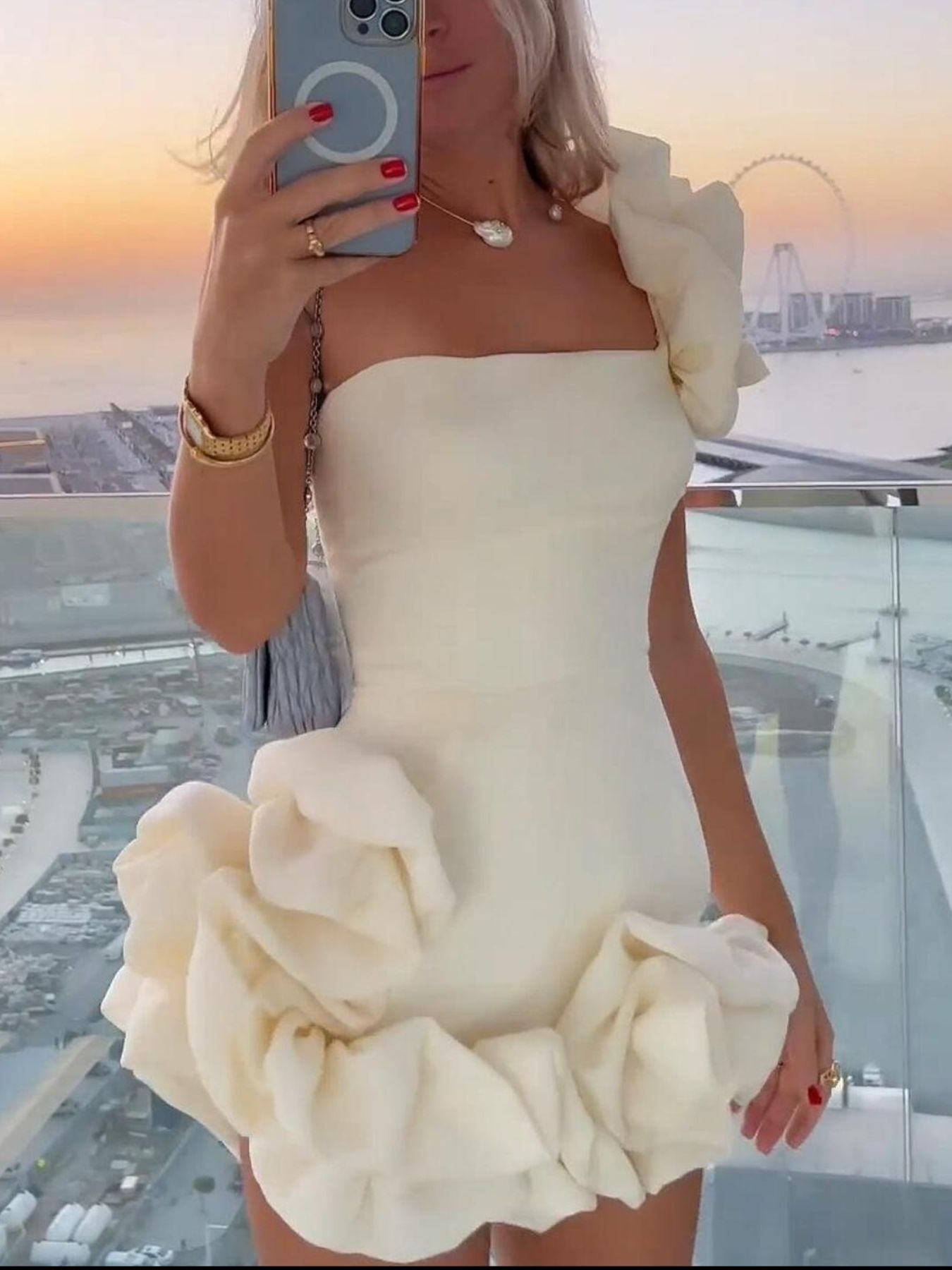 White one-shoulder mini dress with voluminous ruffle hem and shoulder rosette