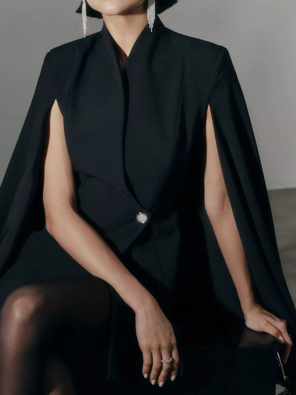 Black fitted mini blazer dress with cape sleeves and one-button closure; front view