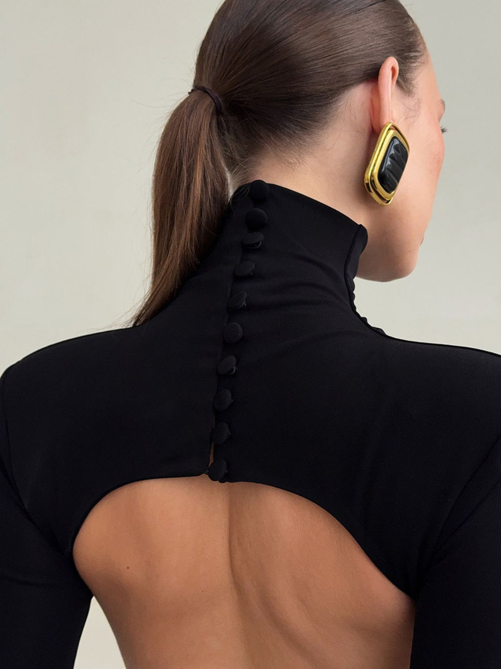 Black backless turtleneck maxi dress with open-back oval cutout and buttoned neck