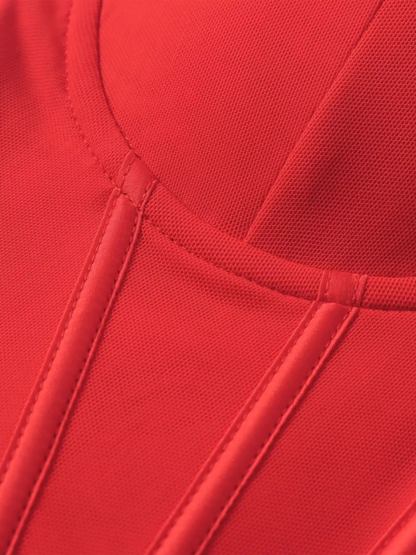 Close-up of red sweetheart bodice seam detailing and ruched vertical paneling