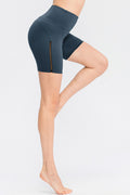 Deep teal wide-waist sports shorts with side trim panel, mid-thigh length