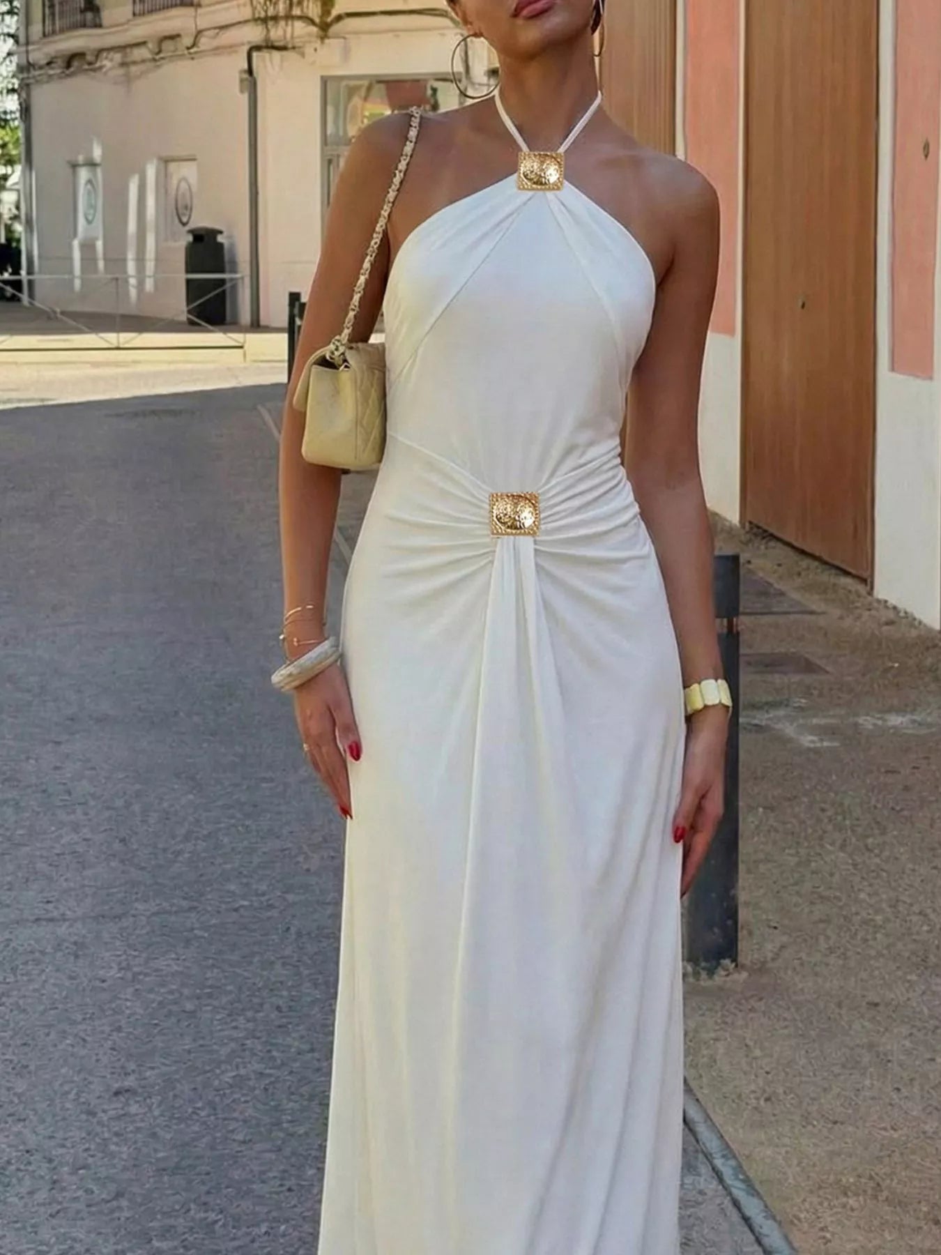 White halter neck backless maxi dress with ruched midsection and flowing skirt.