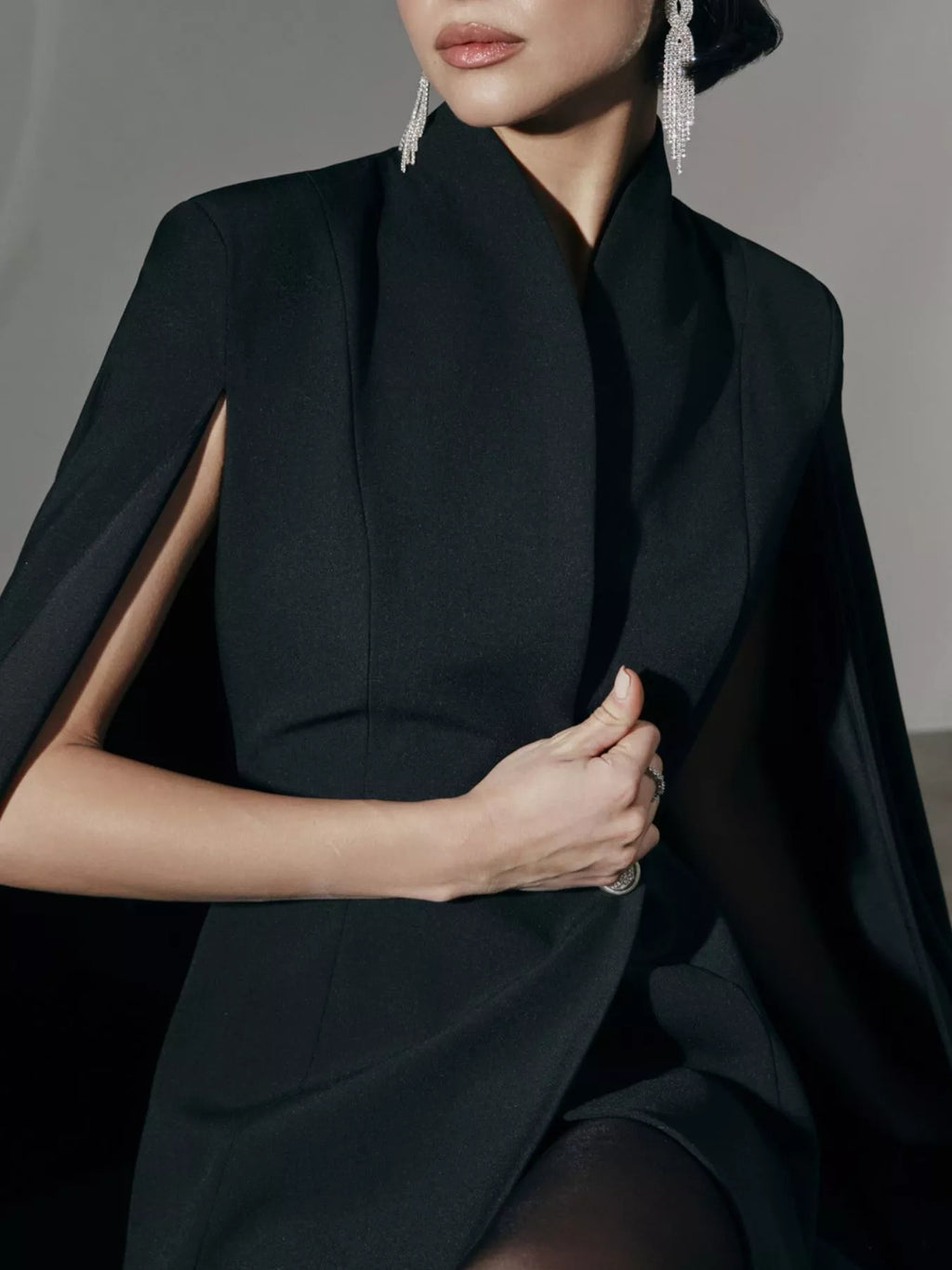 Black blazer mini dress with cape sleeves and one button; high neckline detail