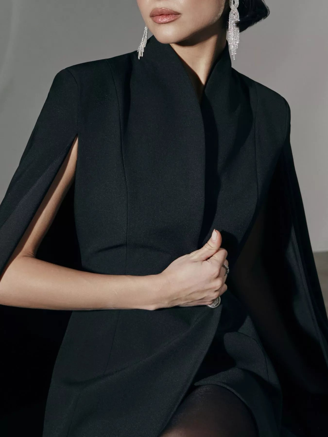 Black blazer mini dress with cape sleeves and one button; high neckline detail