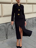 Black long-sleeve midi dress with draped ruffle collar and gold button details.