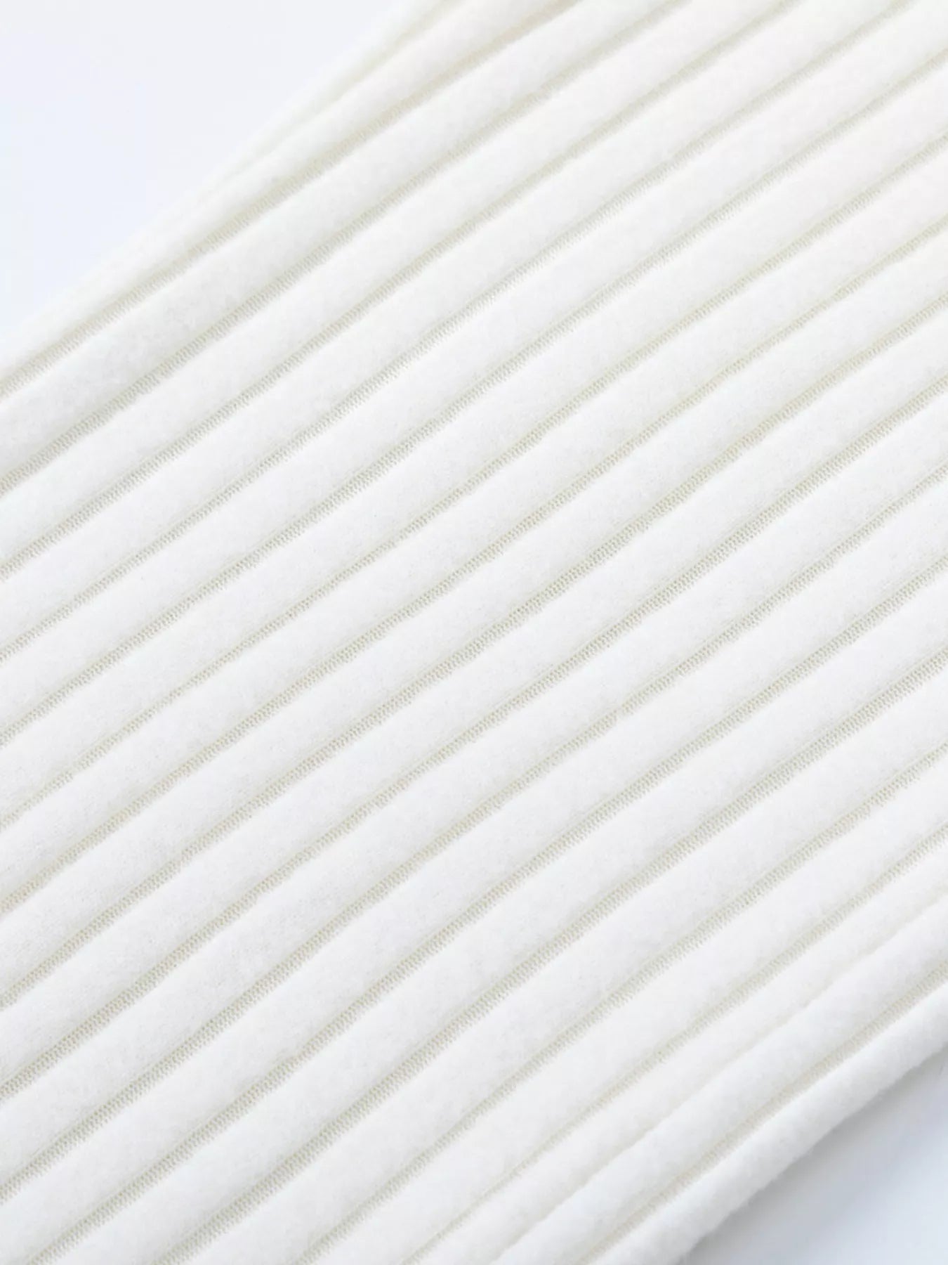 Close-up of white ribbed knit texture with narrow vertical stripes