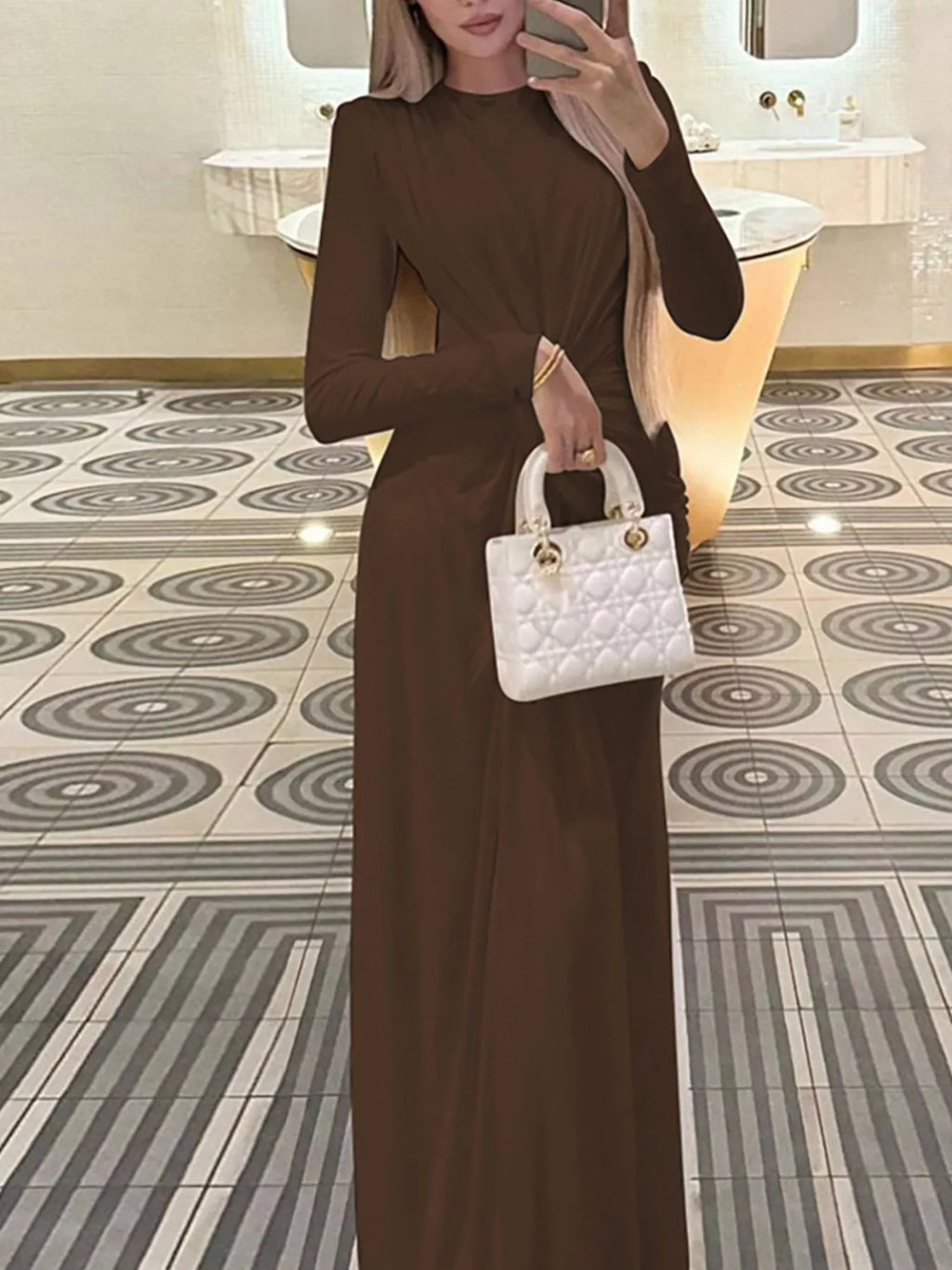 Brown twisted long-sleeve maxi dress with side ruched twist detail and long column silhouette.
