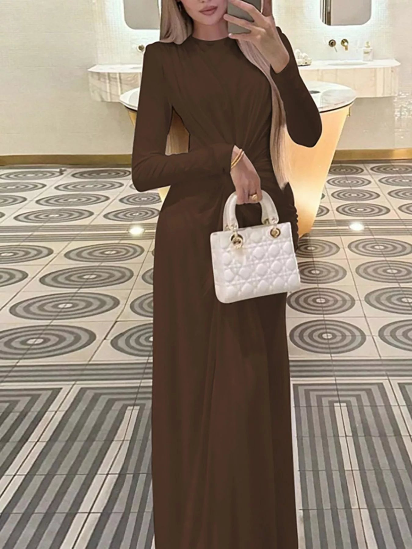 Brown twisted long-sleeve maxi dress with side ruched twist detail and long column silhouette.