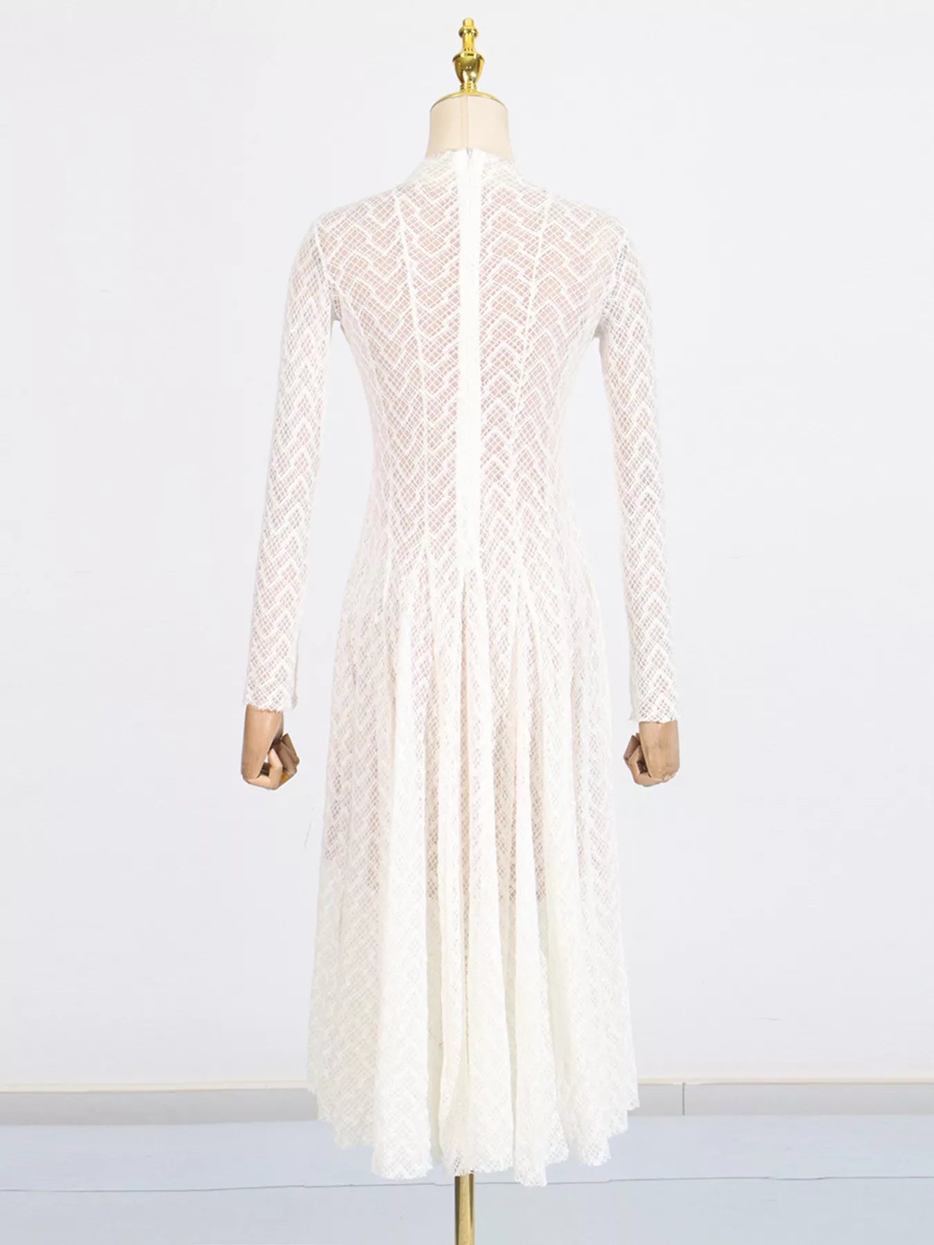 White lace maxi dress on mannequin, long sleeves and flowing full-length hem
