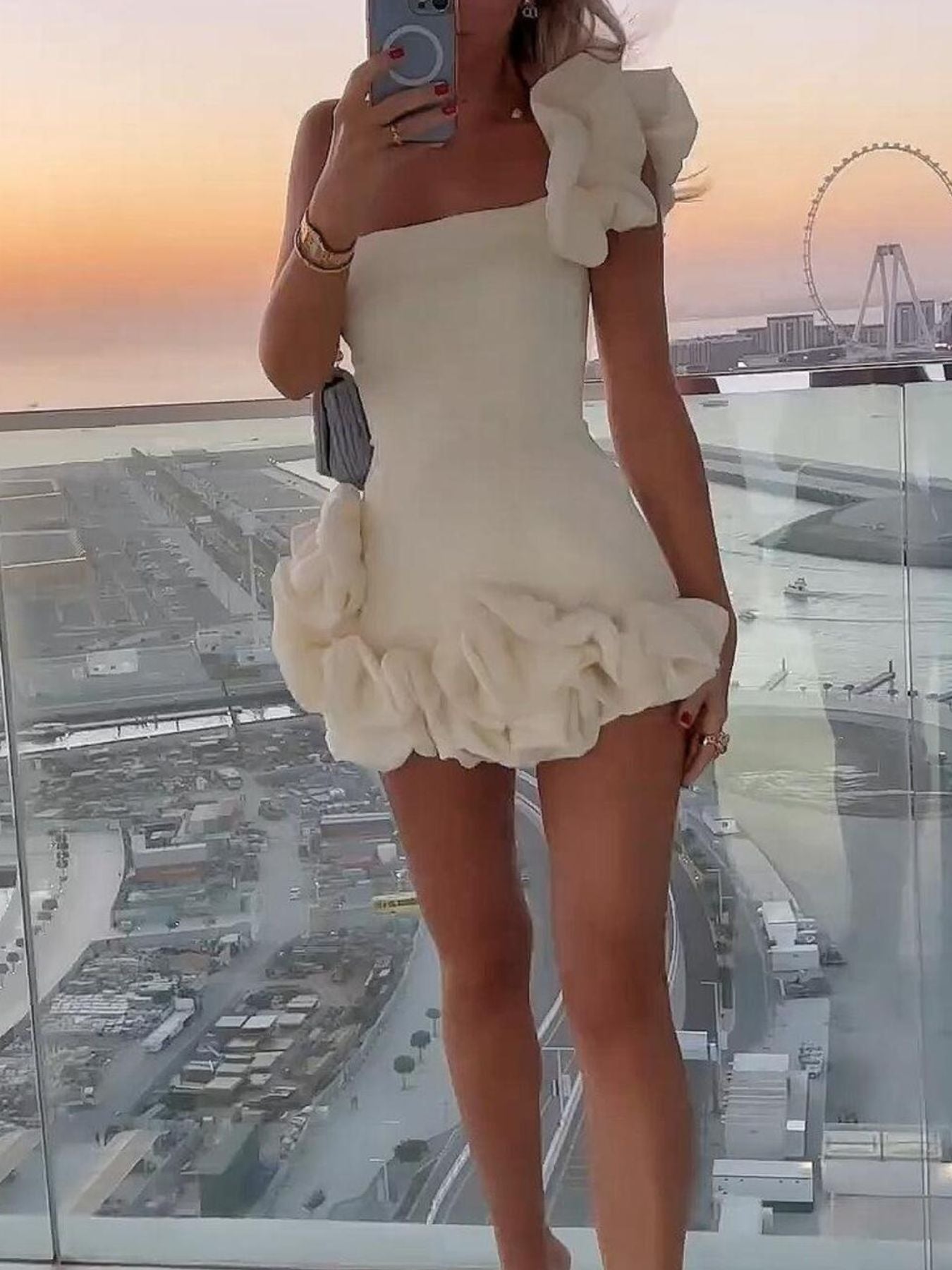 White one-shoulder mini dress with layered ruffle skirt and shoulder flower detail