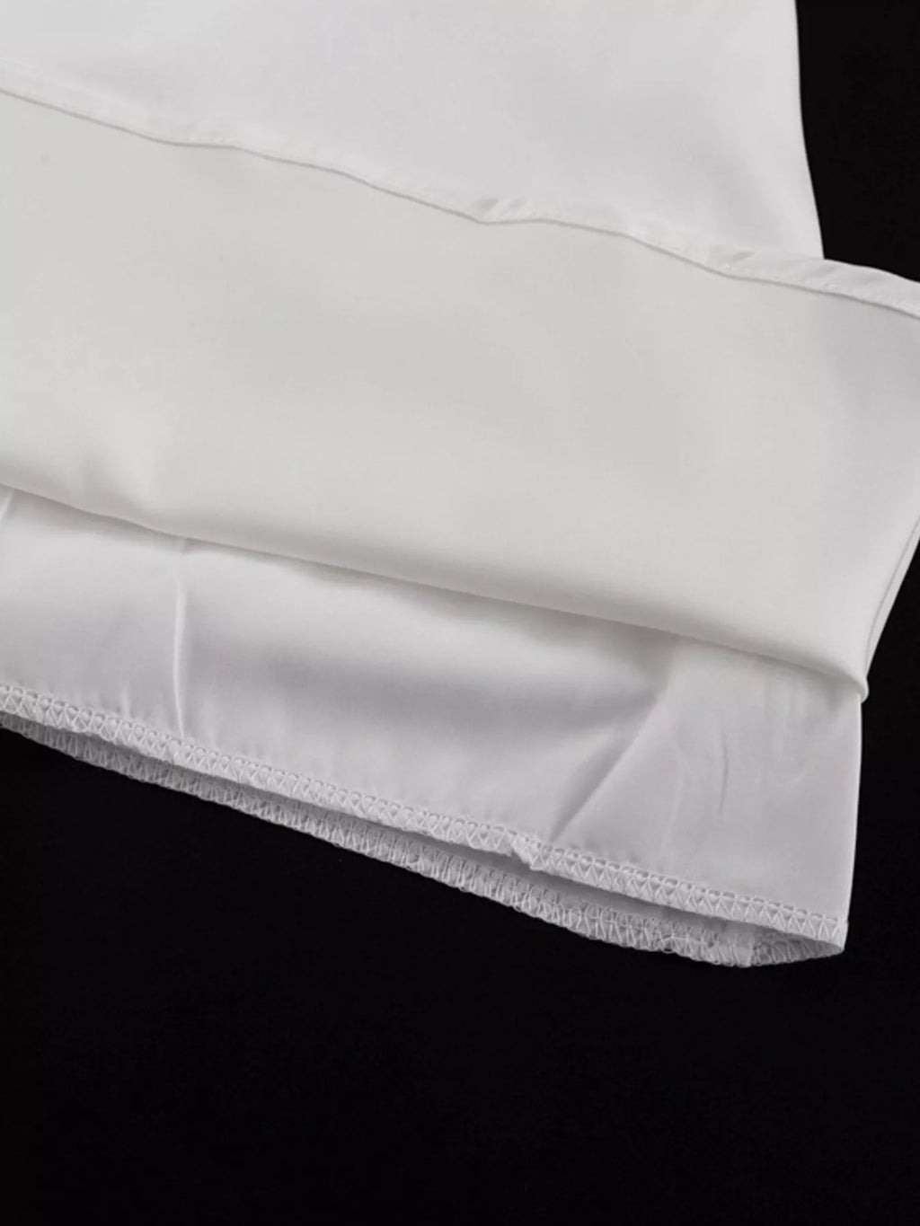 White halter neck mini dress hem close-up with stitched ruffle edge detail