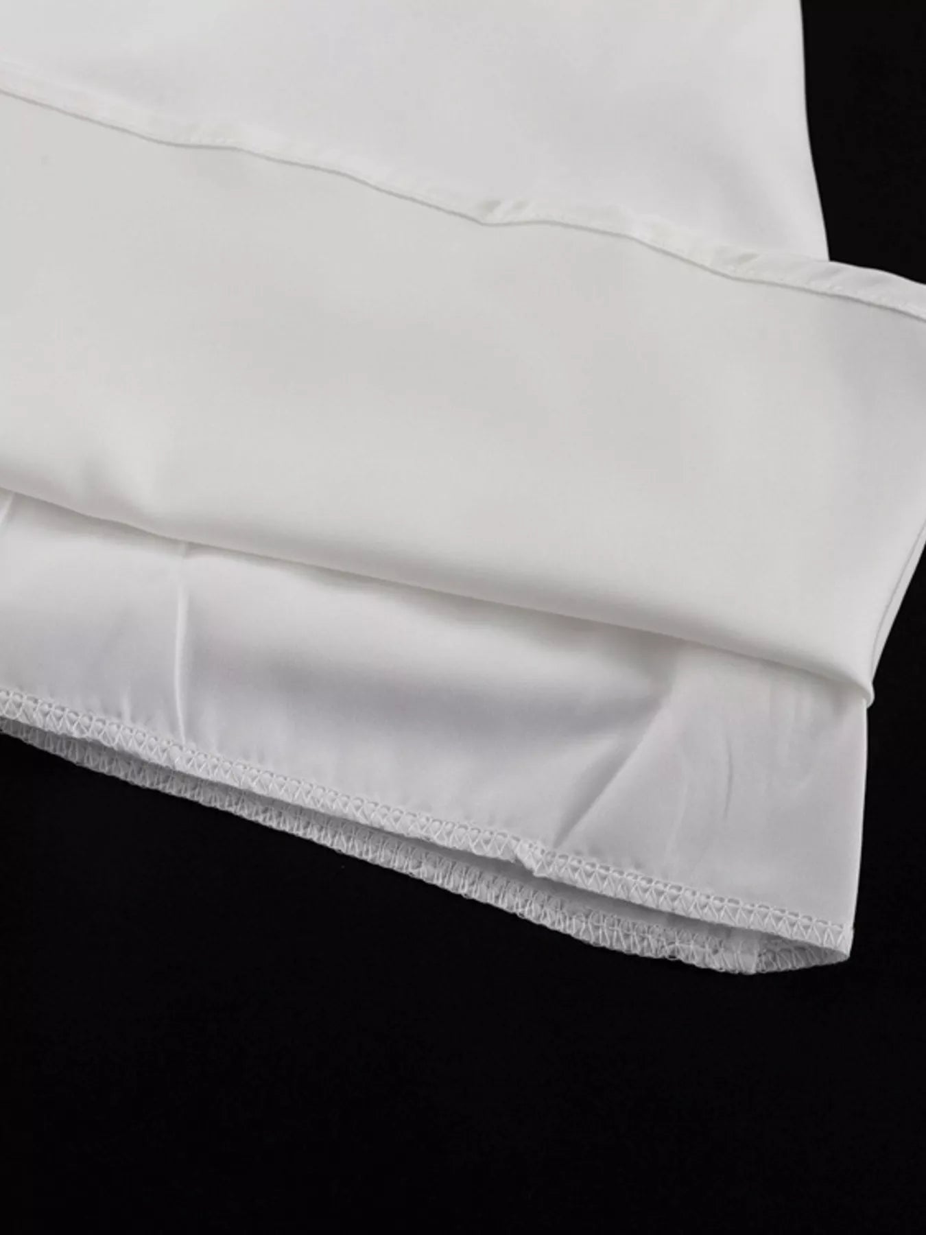 White halter neck mini dress hem close-up with stitched ruffle edge detail