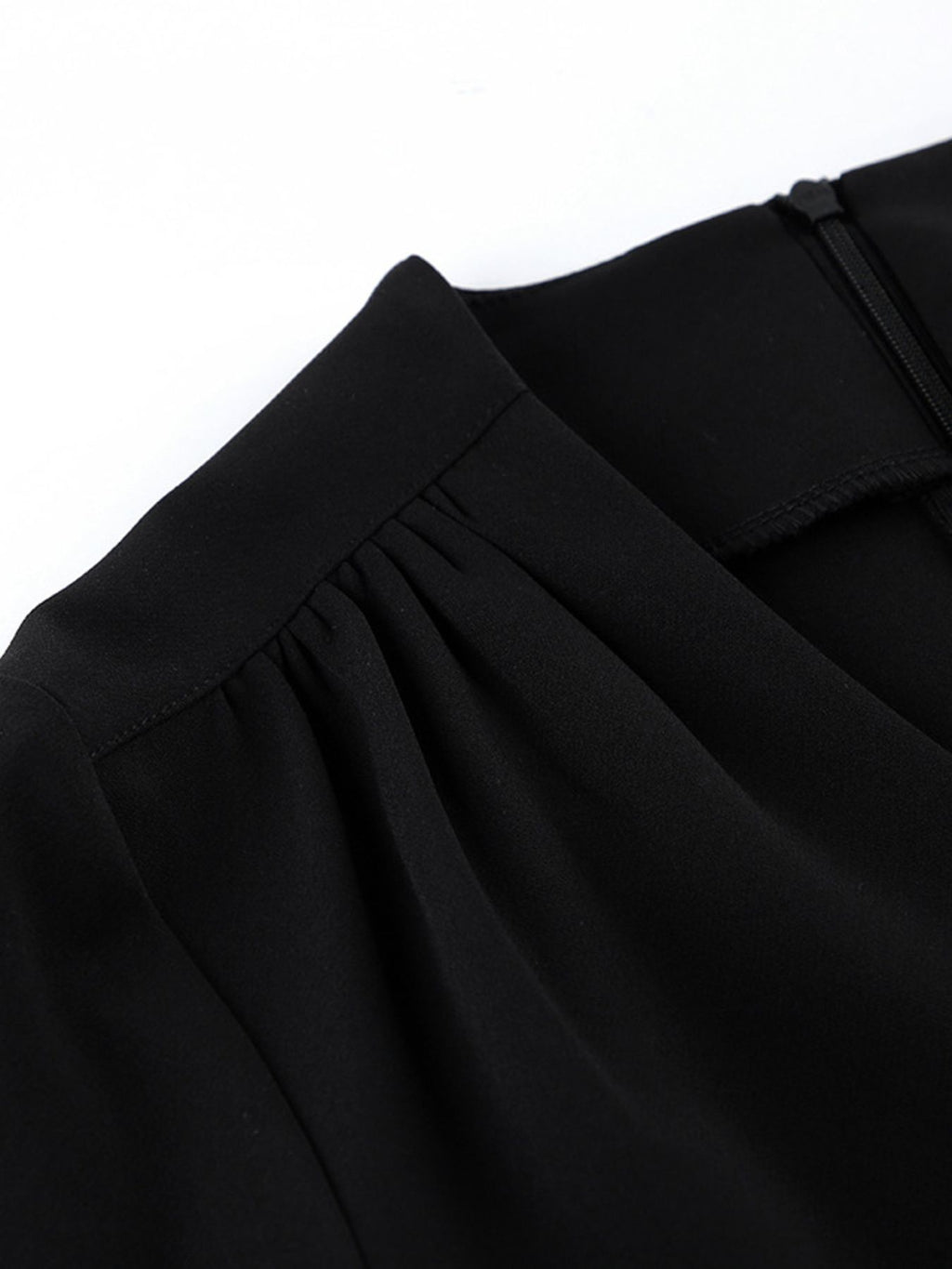 Black dress fabric detail with gathered shoulder and softly pleated neckline trim.