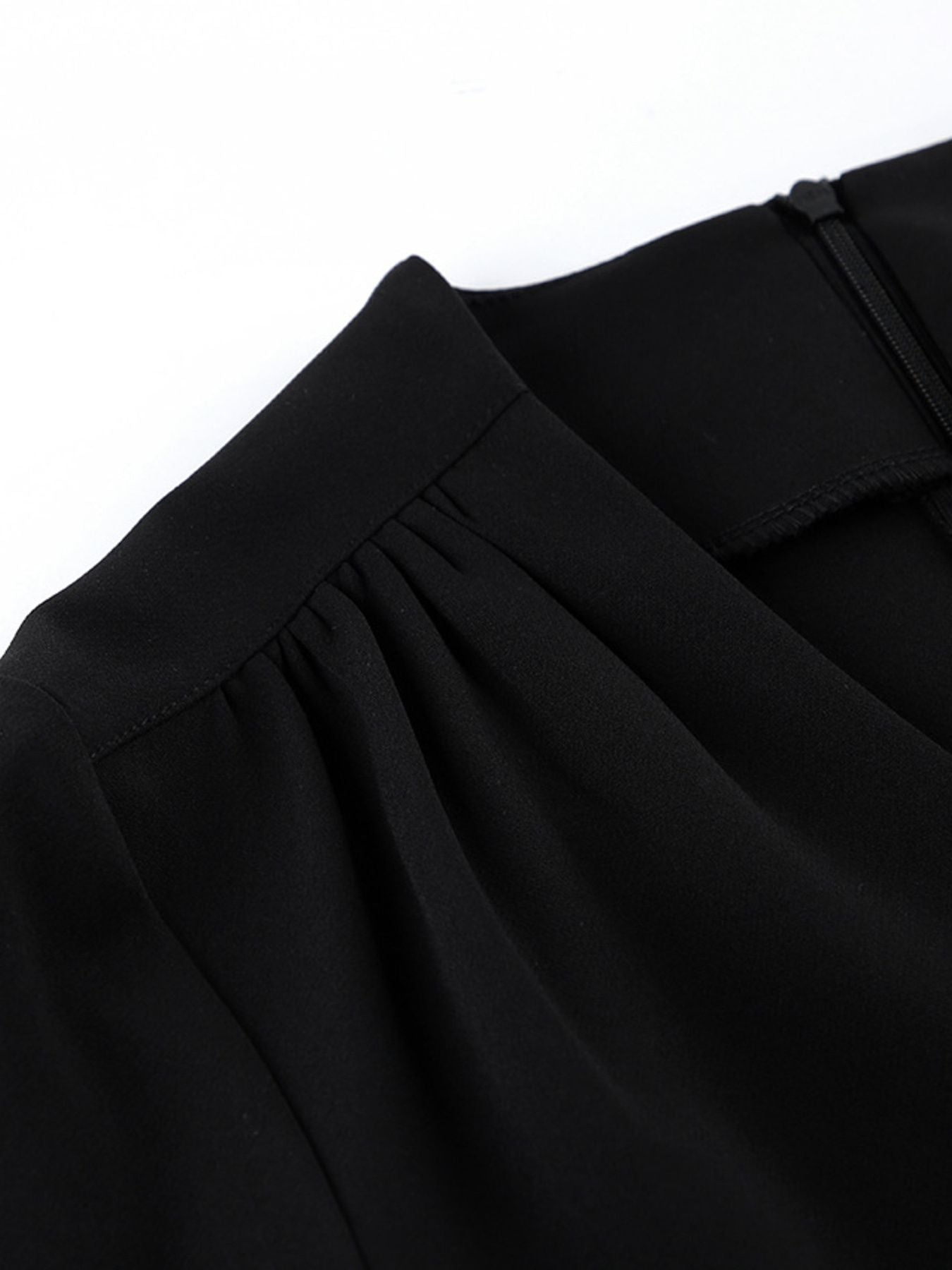 Black dress fabric detail with gathered shoulder and softly pleated neckline trim.