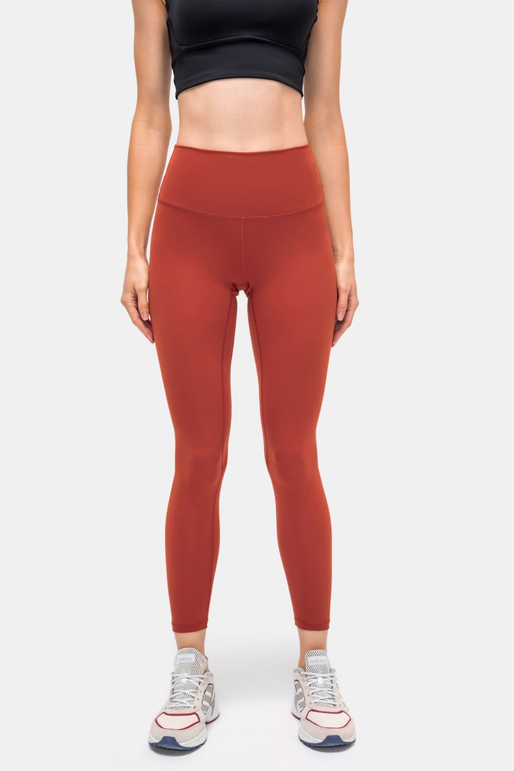 Brick red sports leggings with a smooth waistband and invisible side pocket seams.