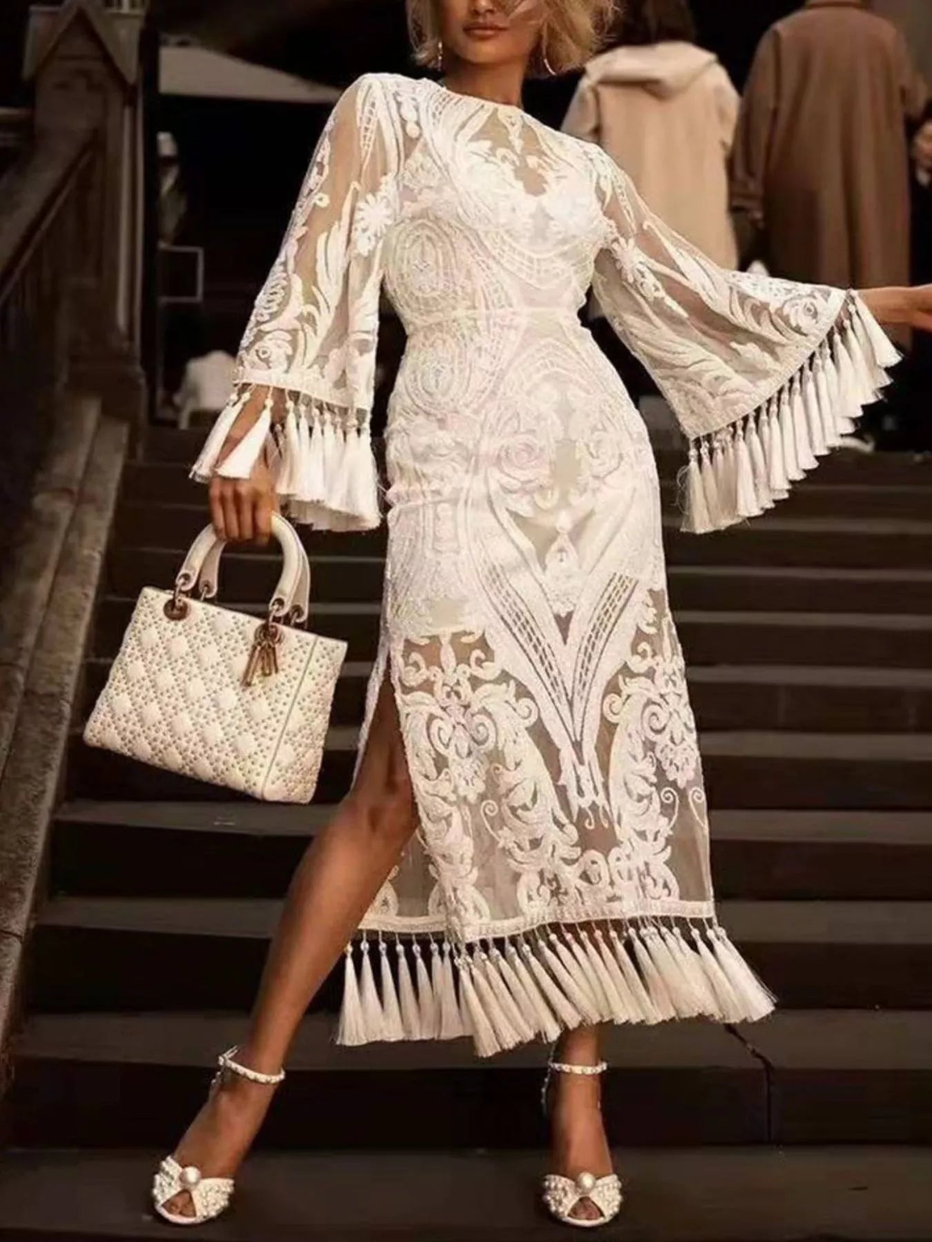 White embroidered lace dress with long flared sleeves and tassel fringe at hem