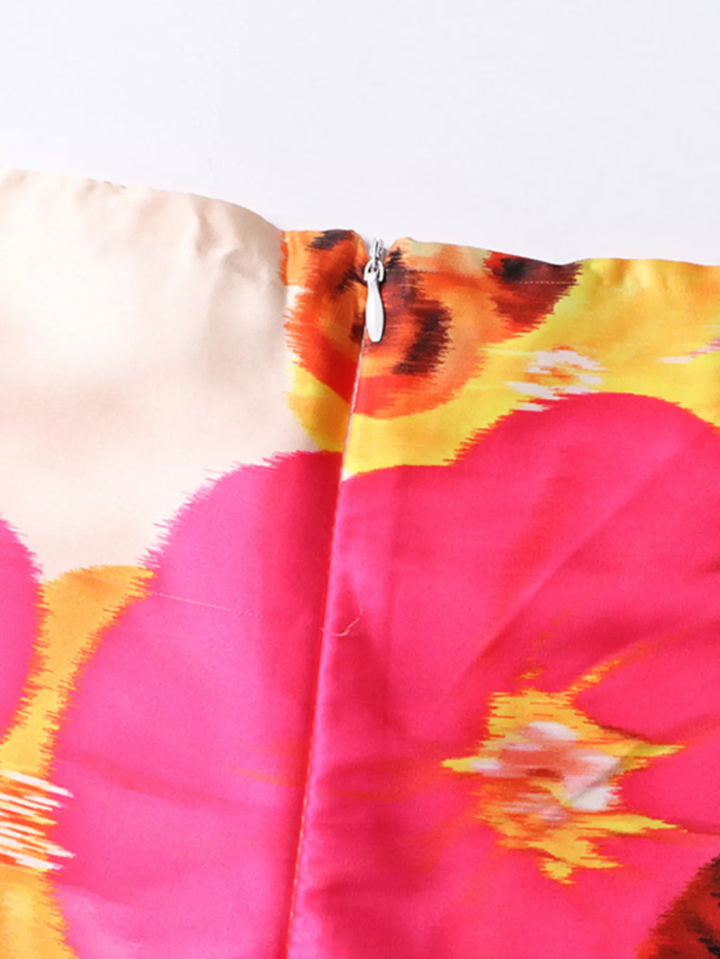 Close-up of floral print fabric with zipper at waist seam on white pants