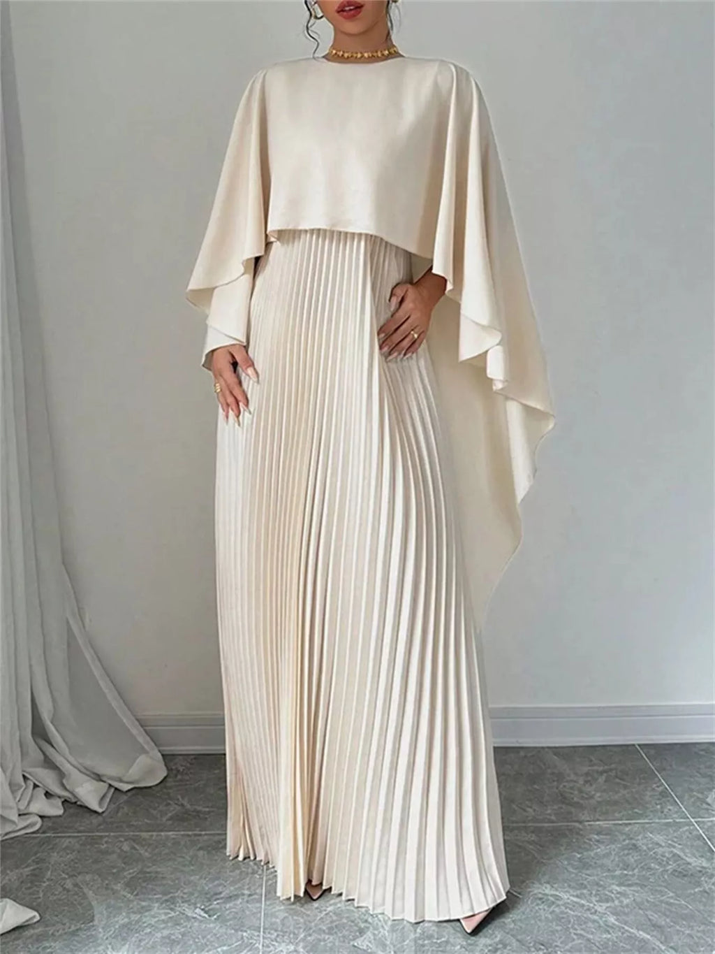 Cream cape pleated maxi dress, draped cape sleeves over a long vertical pleated skirt